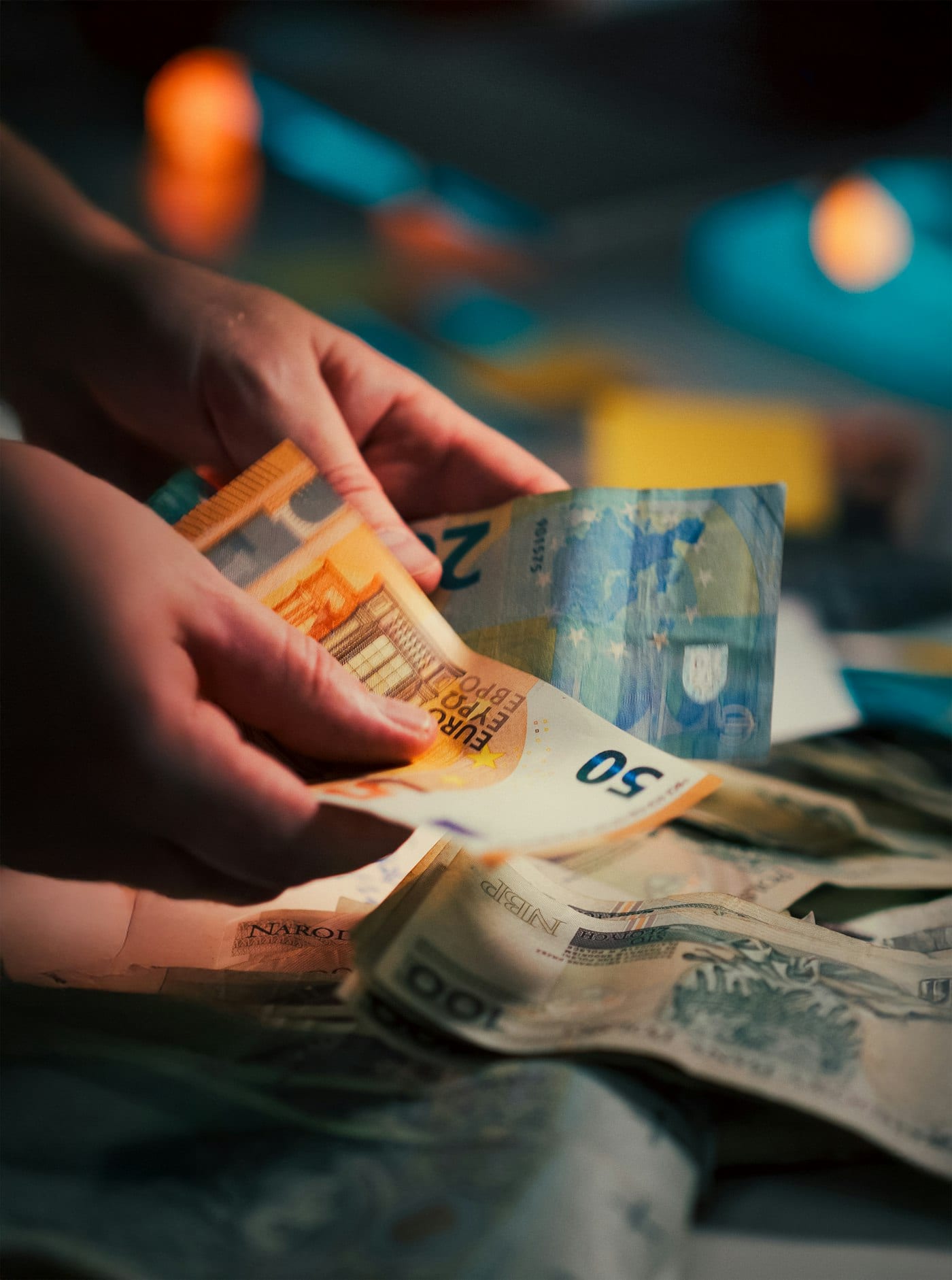 Ruce počítají hotovost z pokladny při zhasnuté provozovně.